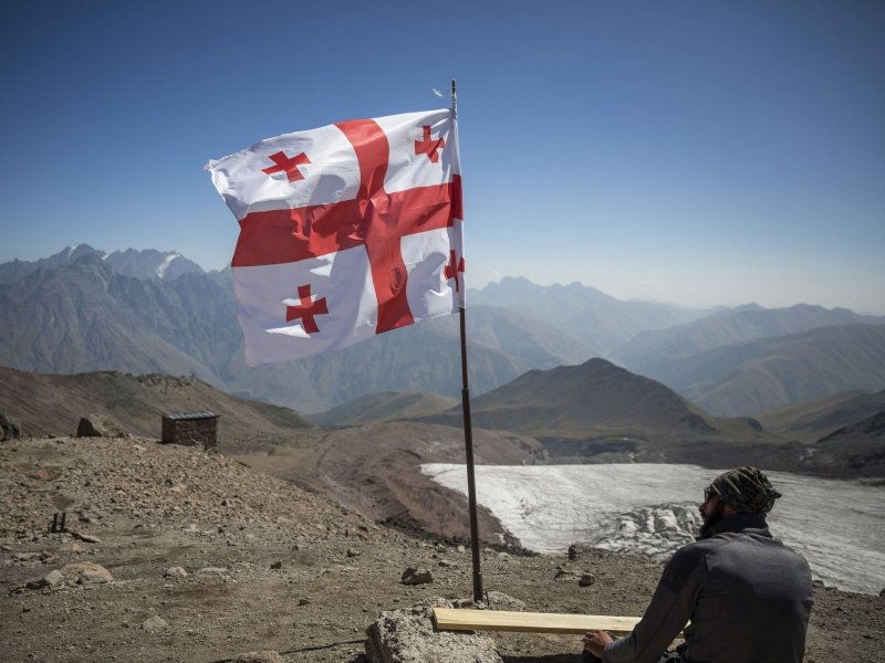 Альпинист отдыхает под флагом Грузии по пути к вершине горы Казбек, 14 сентября 2017 года.