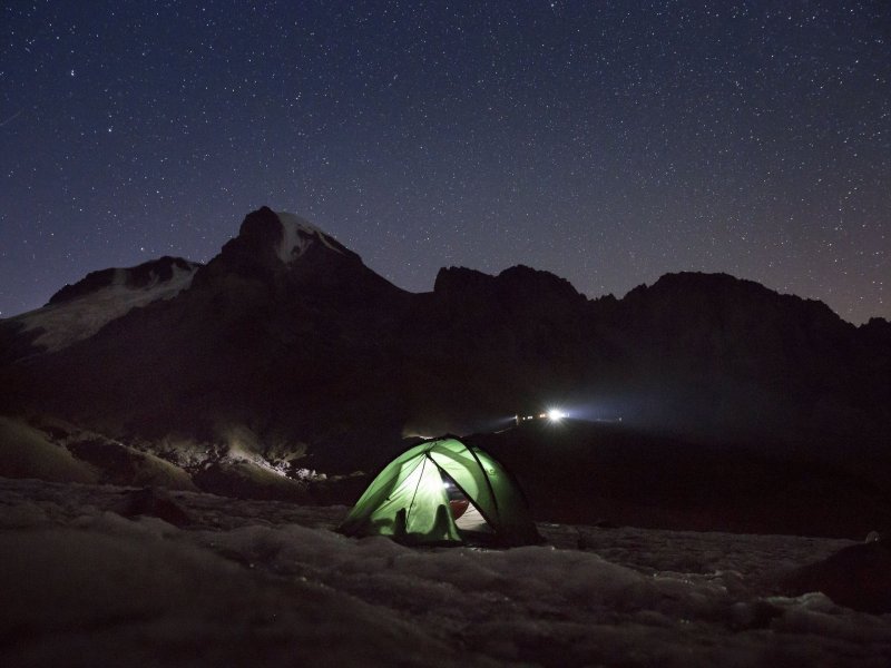 Огонёк уютно светится в палатке, установленной под ночным небом на пути к вершине горы Казбек, 13 сентября 2017 года.