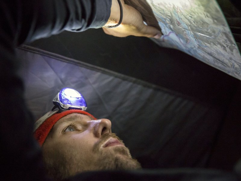 Альпинист Нандор Терек сверяется с картой в своей палатке, установленной на пути к вершине горы Казбек, 12 сентября 2017 года.