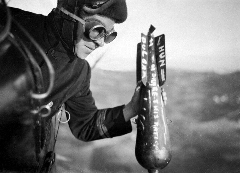 Британский летчик вручную скидывает бомбу на врага во время миссии на Западном фронте. Привычка писать сообщения на бомбах появилась во время Первой мировой войны и сохранилась по сей день.