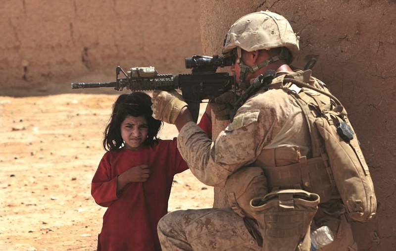 Провинция Гильменд: морпех, целящийся в талибского боевика, и маленькая девочка рядом