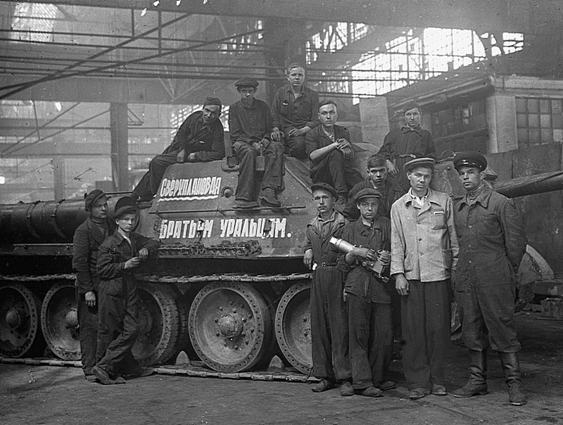 Рабочие в цехе стоят около самоходного орудия САУ СУ-122, изготовленного сверх плана для воинов-уральцев.