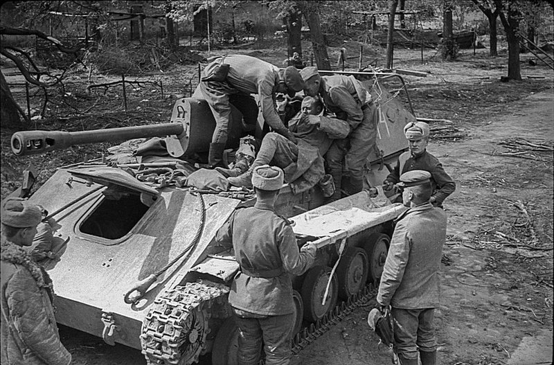 Раненого советского бойца перекладывают с САУ СУ-76М на носилки под Берлином. апрель 1945.
