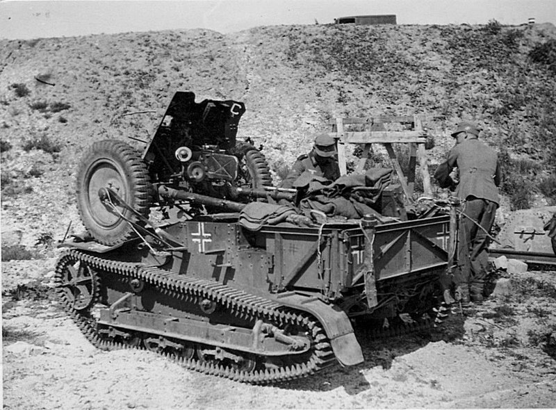 Немецкие солдаты рядом с импровизированной САУ из 37-мм противотанковой пушки PaK 35/36, закрепленной на корпусе французского трофейного многоцелевого транспортера Renault UE.