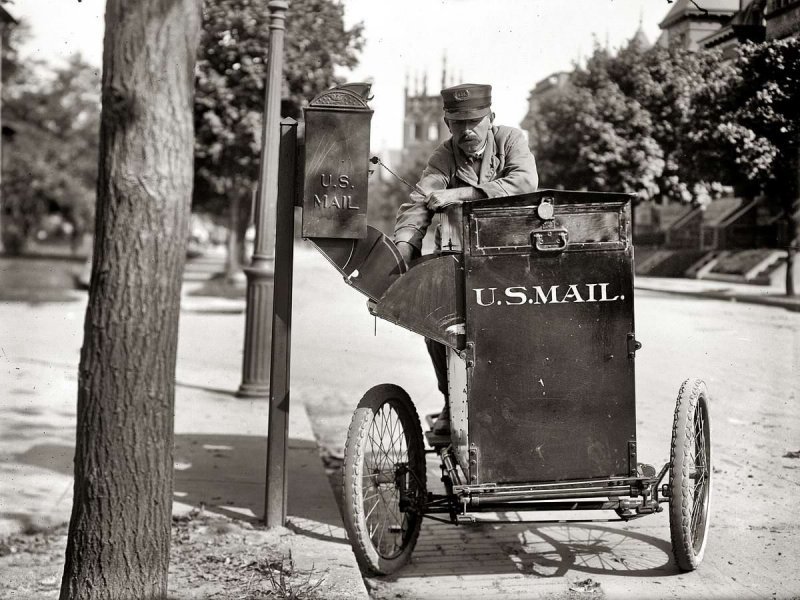Почтальон на трехколесном мотоцикле выбирает корреспонденцию из уличного почтового ящика (Вашингтон, 1912 год)