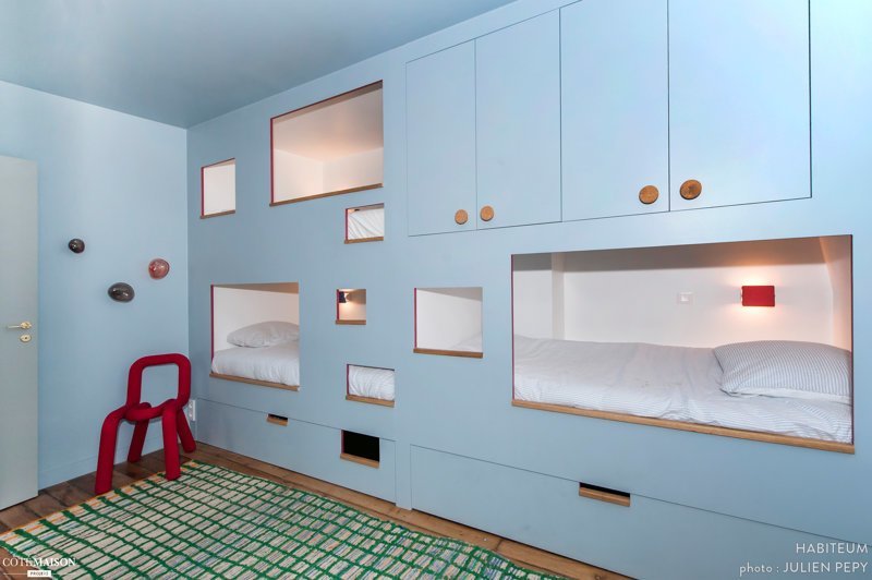 Оригинальный шкваф, расположенный в новой комнате, включает в себя место для хранения вещей и две кровати - они созданы в виде двух ячеек для сна