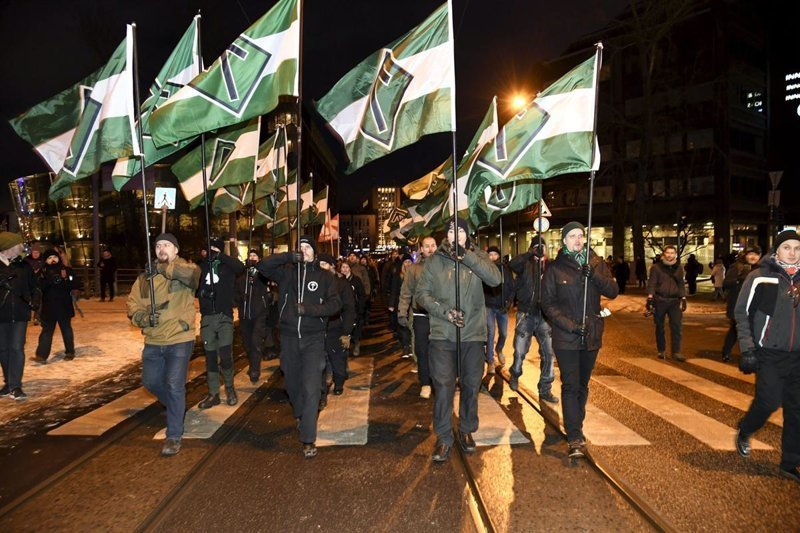 Члены Северного движения сопротивления с флагами, на которых изображен их символ - руна Тир, Хельсинки, Финляндия