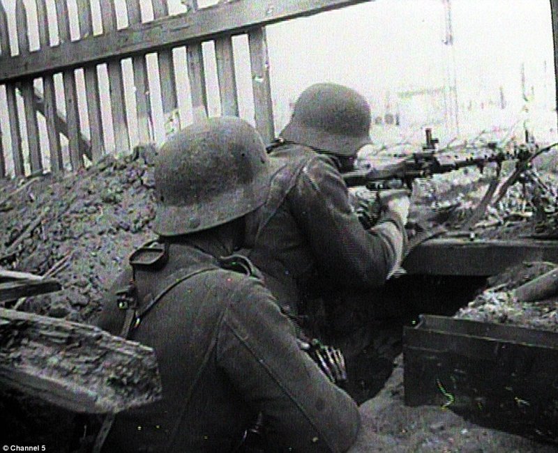 Два немецких солдата стреляют из окопа возле заброшенного здания