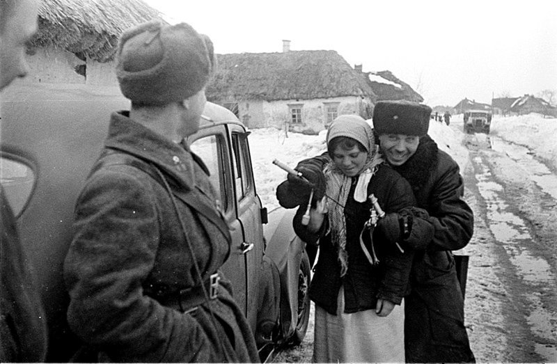 Советские офицеры беседуют с девушкой на сельской улице. Один из офицеров демонстрирует девушке немецкий армейский офицерский кортик обр. 1935 г.