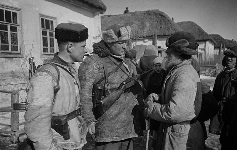 Офицеры 248-й отдельной стрелковой бригады разговаривают с колхозником А. Архиповым в освобожденном селе западнее Курска. Время съемки: февраль 1943.