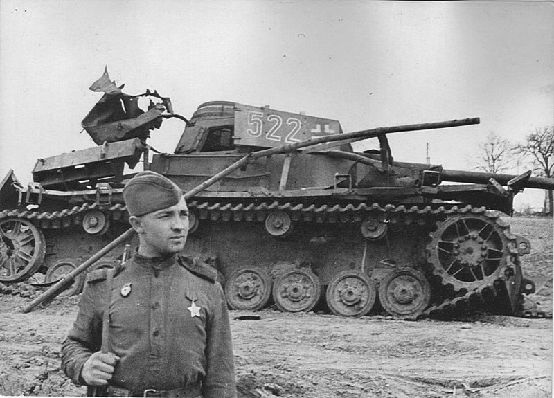 Советский солдат позирует на фоне немецкого среднего танка Pz.Kpfw.IV Ausf. J, уничтоженного на Украине.