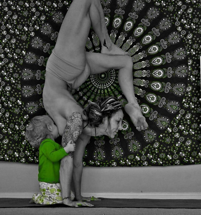 Любительница йоги кормит дочь грудью, стоя вверх ногами