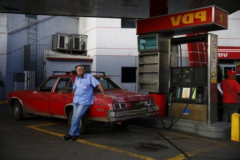 Мужчина заправляет свой Chevy Nova на заправке PDVSA, Каракас, Венесуэла.