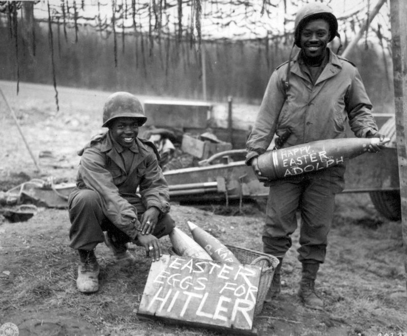 11. Американские солдаты 969-го полевого артиллерийского батальона украшают пасхальными надписями ("пасхальные яйца для Гитлера", "счастливой Пасхи, Адольф") снаряды, которые полетят в сторону Германии, 1944 г.
