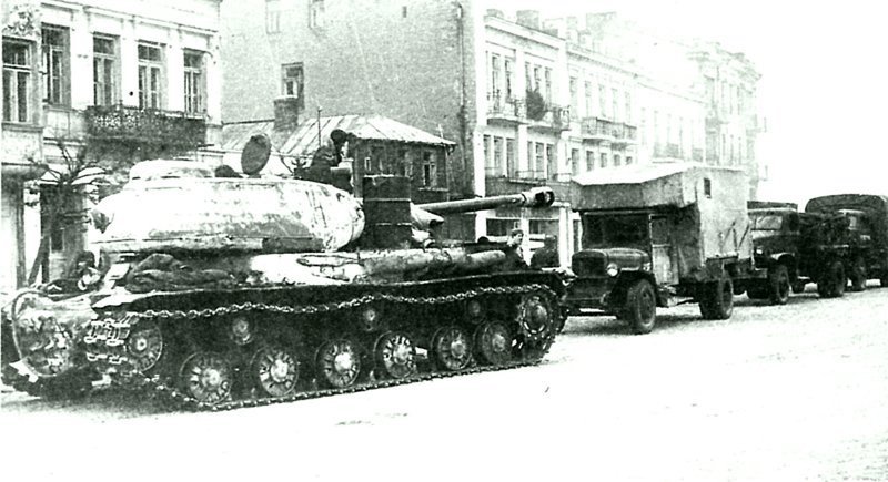 Танк ИС-2 во главе автомобильной колонны на улице города Млава. В колонне автофургон на базе грузового автомобиля ЗиС-5, грузовые автомобили Chevrolet G7107 и Studebaker US6.  Польша, январь, 1945 