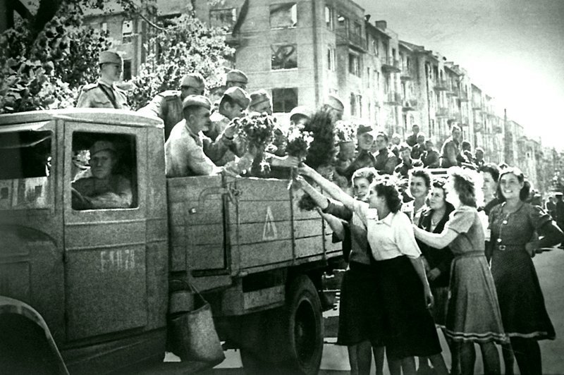Девушки дарят цветы красноармейцам в кузове грузовика ЗиС-5 на улице освобожденного Харькова.  Украина, СССР.  Время съемки: август 1943  