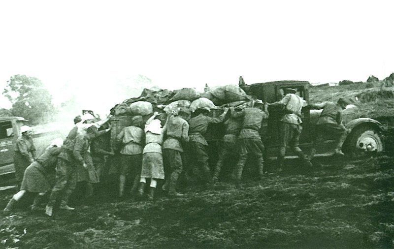 Советские солдаты, в том числе женщины, толкают застрявший в грязи грузовик ЗиС-5. Время съемки: 1943.  Автор: Иван Шагин