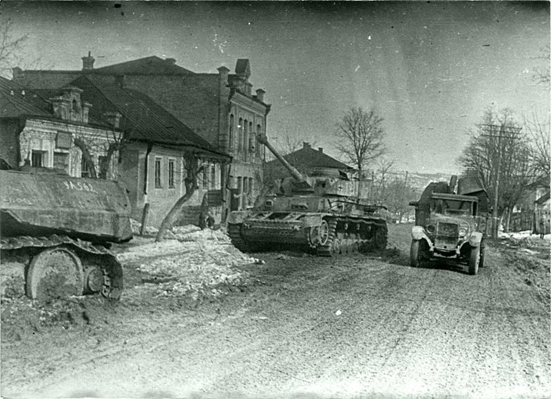 Советский грузовик ЗиС-5 проезжает мимо брошенного немецкого танка Pz.Kpfw. IV в городе Проскуров (Хмельницкий). Слева видна задняя часть немецкого танка «Пантера».  Украина, апрель 1944 