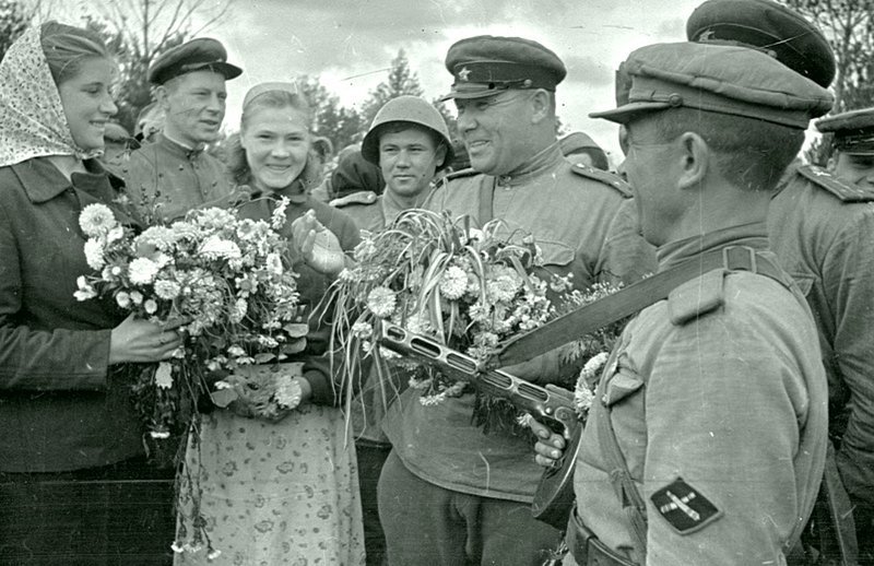 Девушки встречают цветами советских военнослужащих истребительно-противотанковой артиллерии.