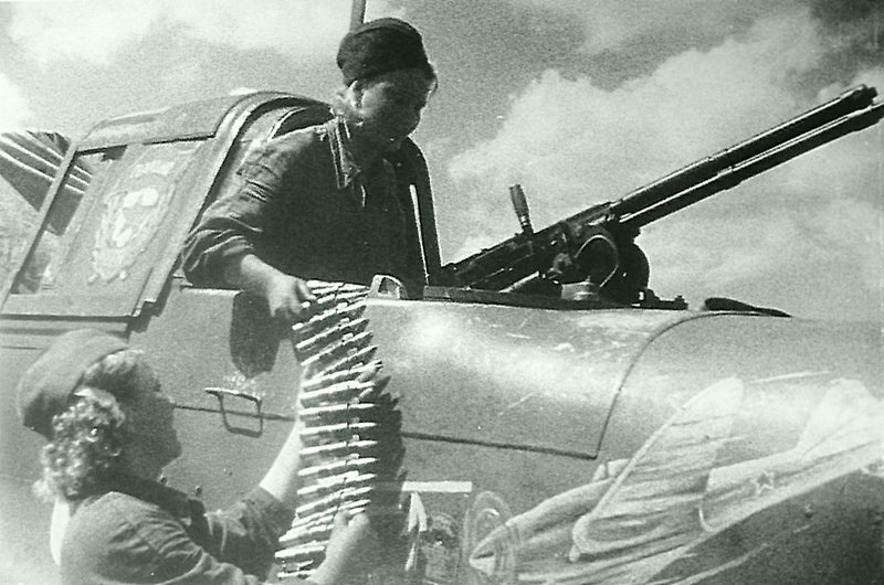 15. Девушки-оружейницы заряжают пулемет УБТ штурмовика ИЛ-2 капитана В.Б. Емельяненко.  Время съемки: 1943.