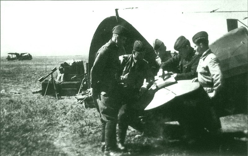 Капитан С.М. Капицын объясняет цель предстоящего боевого задания пилотам Оськину и Гаврилову, стоя у самолета И-153 «Чайка». Время съемки: 1943.  