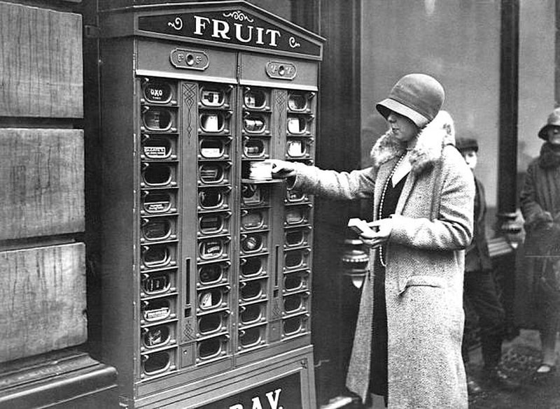 Торговый автомат в Англии в 1920 году, который распределяет фрукты, кубики Oxo, другие банки с продуктами питания, спички и продукты Colgate.