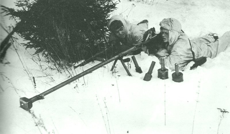 Советские бронебойщики с противотанковым ружьем системы Дегтярева (ПТРД-41) в засаде во время битвы за Москву. Бронебойщик производит заряжание, кладет один патрон в приемник ствольной коробки. декабрь 1941. 