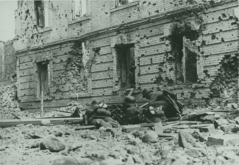 Трое немецких солдат у установленного на станке пулемета MG-34 у полуразрушенной кольцевой казармы в районе Холмских ворот в Цитадели Брестской крепости. Время съемки: июнь-июль 1941. 