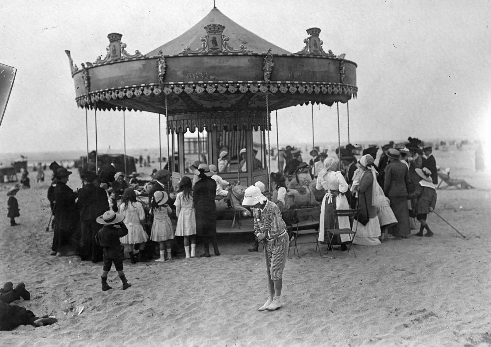 Люди вокруг карусели на пляже, 1900 г.