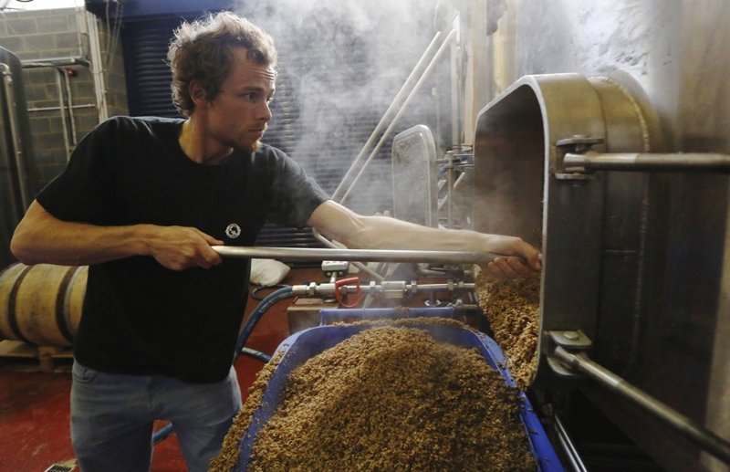 Пивовар Кригл Люты вычищает из сусляного чана солод и отработанные злаки во время приготовления индийского светлого эля в микропивоварне The Kernel Brewery, Лондон, Англия