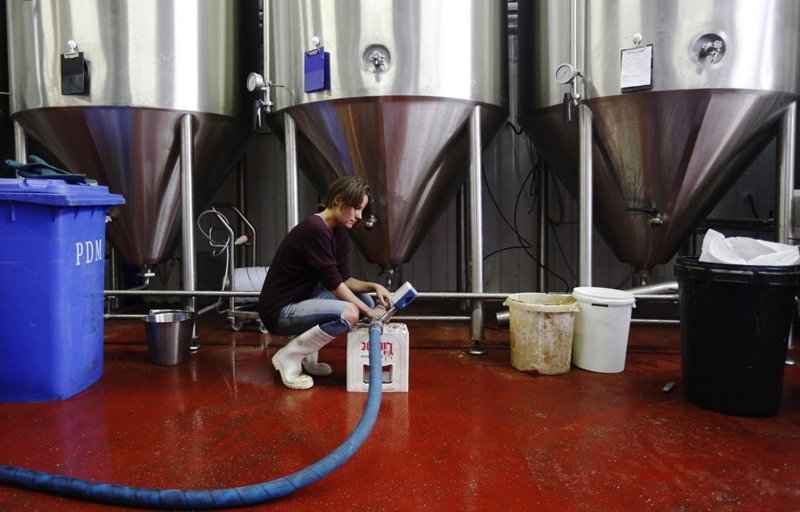 Пивовар Джоби Уильямс проверяет, как пиво поступает по трубам в бродильные чаны.