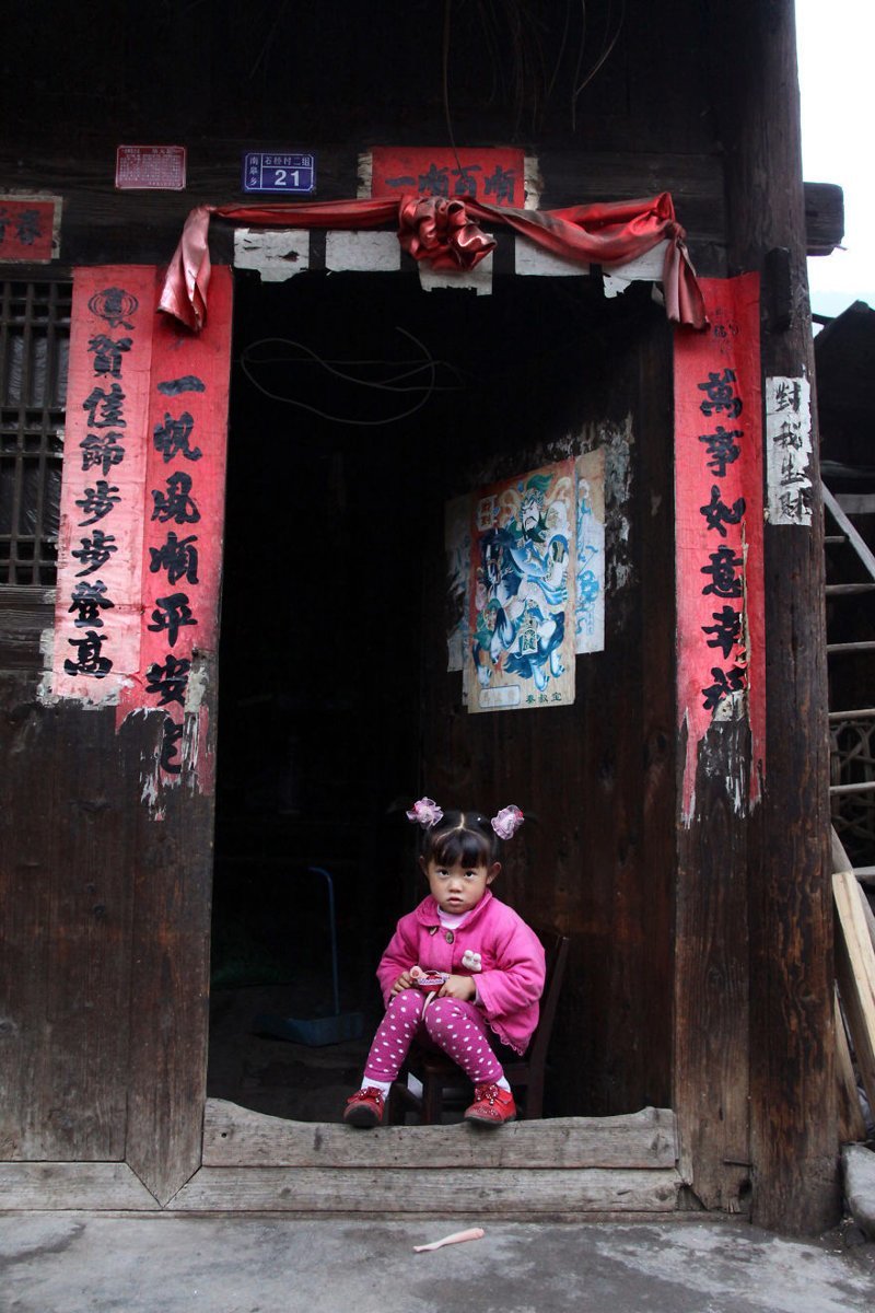2. Девочка позирует у входа в свой дом. Шицяо, провинция Гуйчжоу, Китай