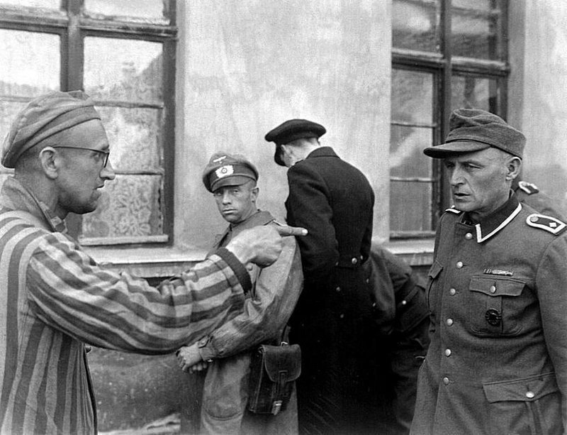 Освобожденный узник указывает на нацистского охранника, который жестоко издевался над  заключенными в концентрационном лагере Бухенвальд. 1945