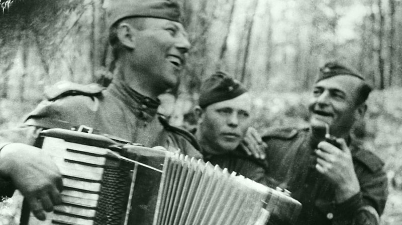 31. Бойцы 311-й стрелковой дивизии слушают товарища, играющего на аккордеоне в День Победы в Германии.