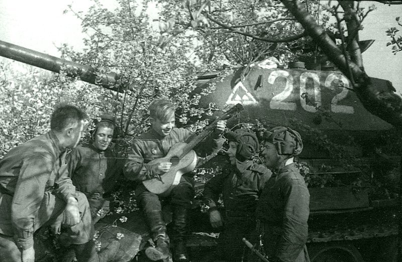 29. Советские танкисты у танка Т-34-85 в Берлине 9-го мая 1945 года слушают товарища, играющего на гитаре.