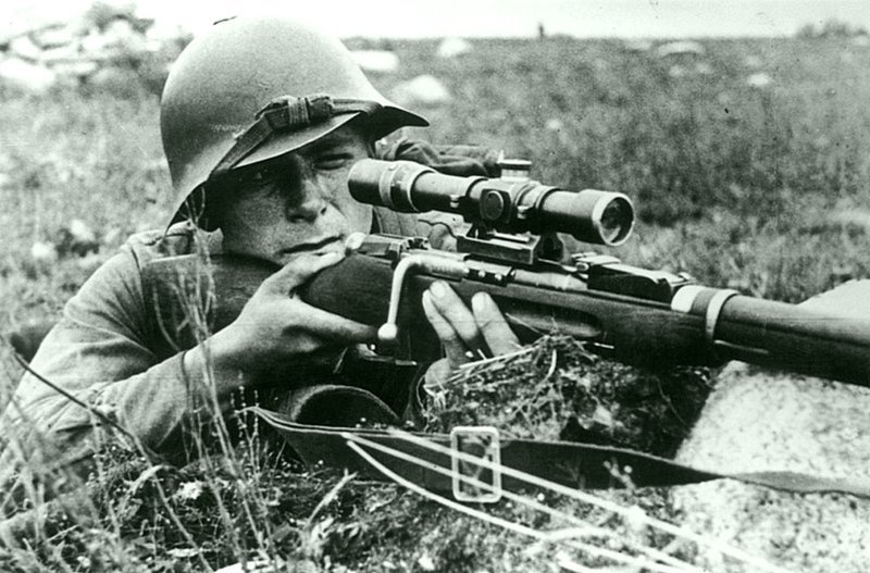 Советский снайпер В.А. Сидоров на огневой позиции в 1941 году. Красноармеец вооружен снайперской винтовкой Мосина с оптическим прицелом ПЕ образца 1931 года, стоит отметить так же каску-«халкинголку» СШ-36.