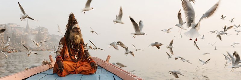 Садху (святой человек) на лодке в Варанаси, Индия