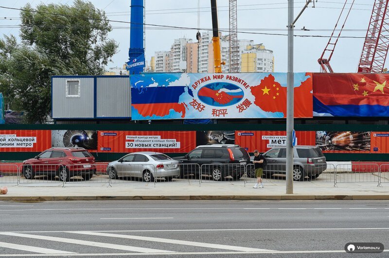 Рядом стройку метро прикрывают плакаты о российско-китайской дружбе.