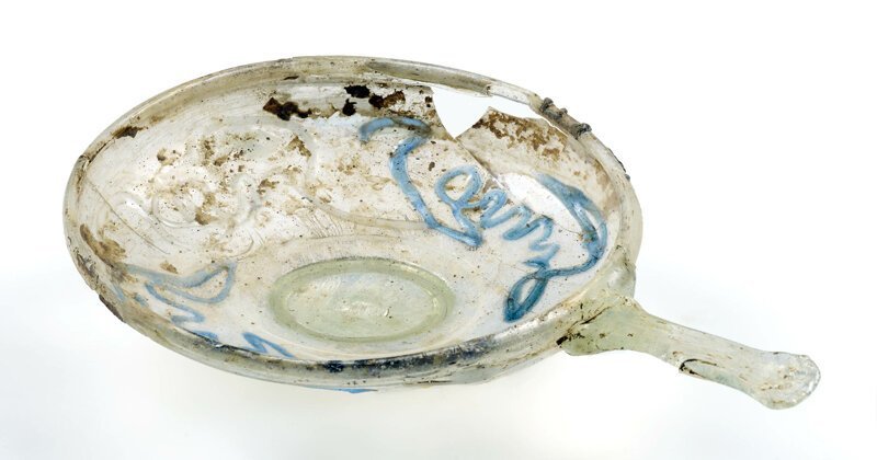 Косметическое стеклянное блюдце, украшенное голубой глазурью, с ручкой. Возможно, использовалось для смешения масел и духов. 