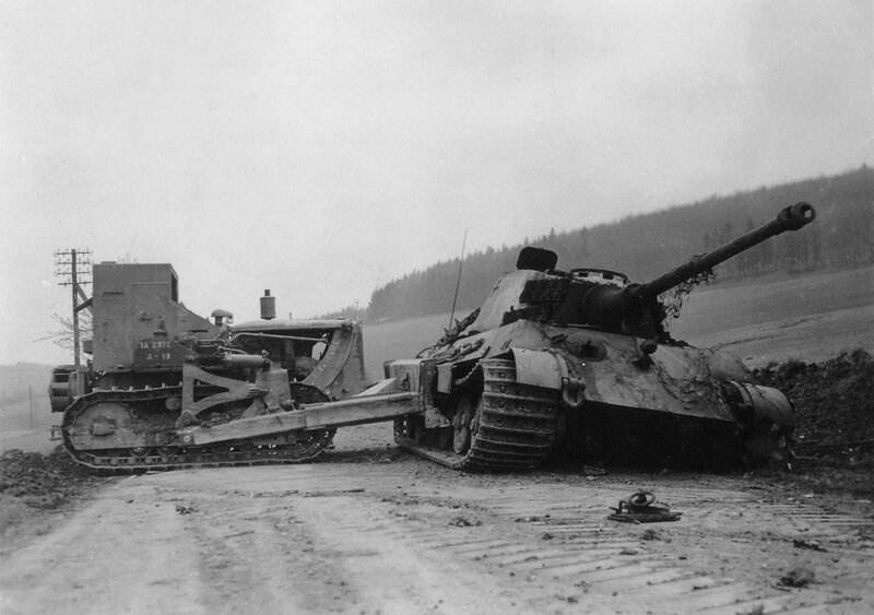 Американский бульдозер D7 из 1-го инженерного батальона 1-й армии сталкивает уничтоженный немецкий тяжёлый танк "Королевский тигр" из 507 тяжёлого танкового полка на обочину. Окрестности Остероде, Германия, 12 апреля 1945 г.