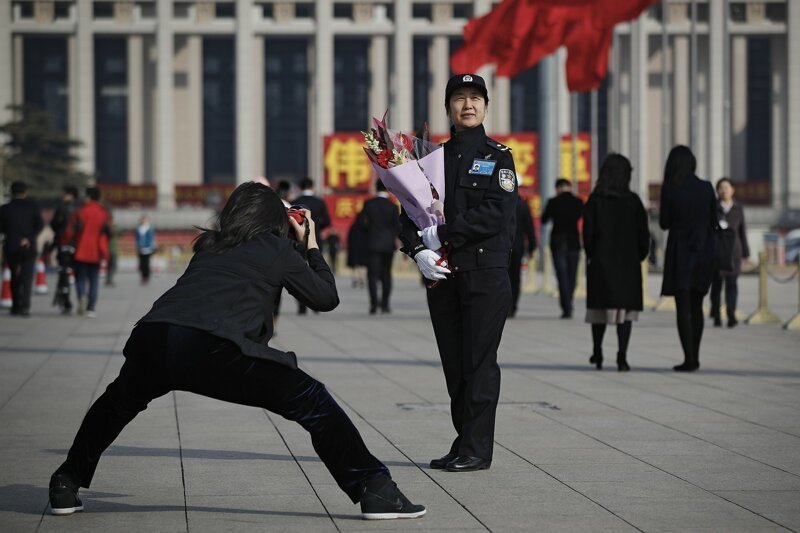 17. Женщина-полицейский позирует с букетом цветов на площади Тяньаньмэнь. Пекин, Китай, 8 марта 2019 года