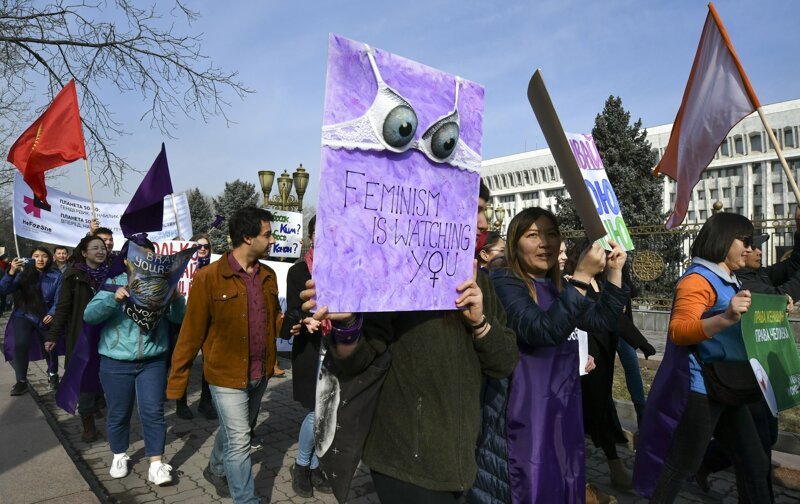 8. Люди с плакатами идут через центр столицы Кыргызстана Бишкек. Справа - здание правительства