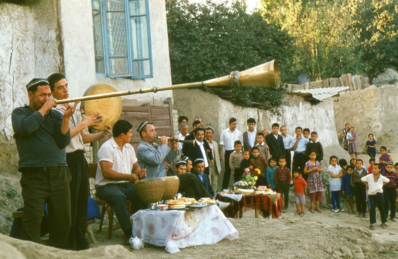 Самарканд. Перед домом четверо узбеков играют народную музыку с традиционными инструментами, чтобы привлечь внимание прохожих к свадебному торжеству