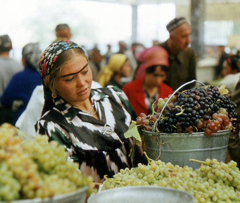 Самарканд. Женщина внимательно изучает виноград, предложенный торговцем на рынке