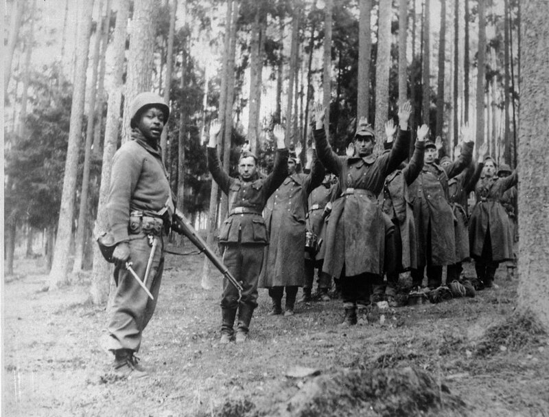 Американский солдат из 12-й бронетанковой дивизии рядом с группой пленных немцев где-то в лесу в Германии, апрель 1945 года. 