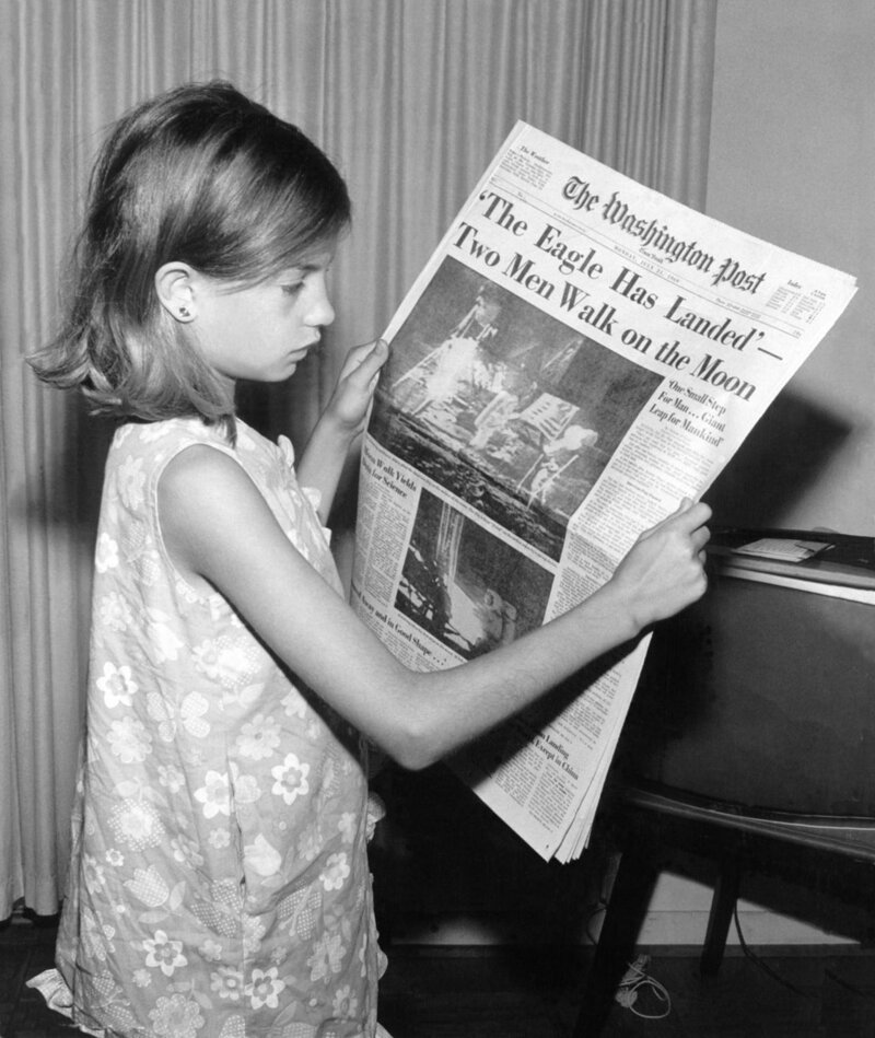 Девочка, читающая титульный лист газеты «Вашингтон пост» с сообщением о посадке на Луну «Аполлон-11». 