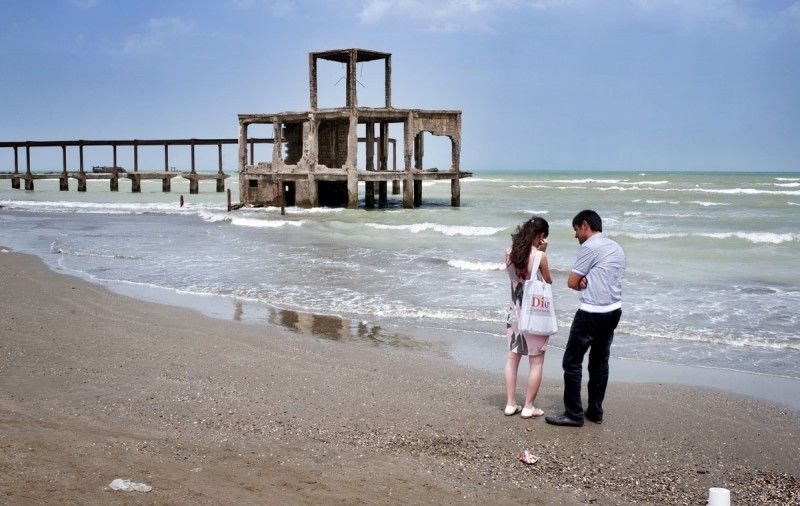 Пара спорит на берегу, на фоне — заброшенный советский ресторан. Сумгаит, Азербайджан.