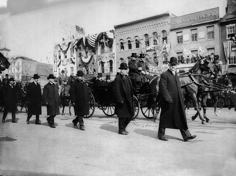 Агенты секретной службы ходят по обеим сторонам экипажа президента Теодора Рузвельта во время его инаугурации 4 марта 1905 года. Он был первым президентом, которому была предоставлена ​​защита секретной службы.