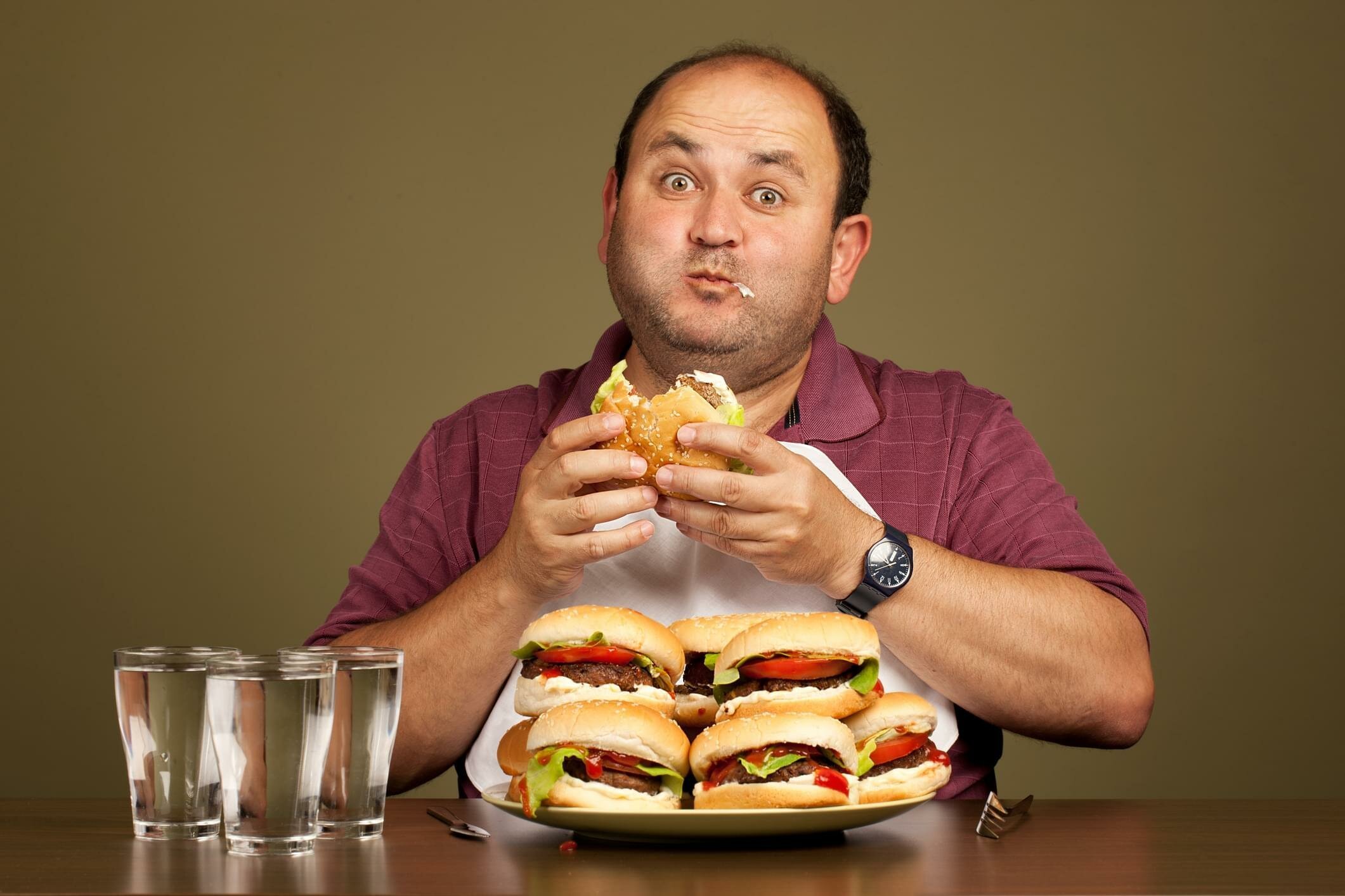 Толстый голодный. Переедание. Человек ест гамбургер. Человек с едой. Мужчина и много еды.