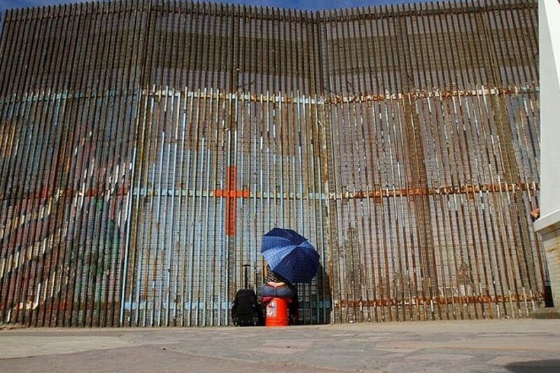 Жительница Мексики общается через забор с родственниками на границе с США